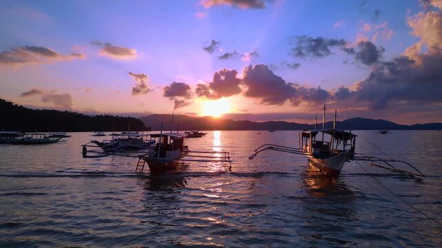 Traditional bancas in Port Barton bay during sunset. Dramatic aerial view drone