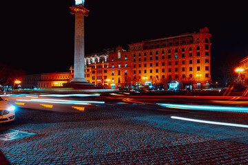 Fototapeta premium City street at night with moving cars and illuminated buildings in the background