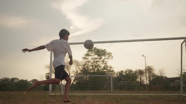 Young boy standing with soccer ball looking at goal during sunset, imagining future success as professional football player. Concept of dream, vision, motivation, and cinematic storytelling.