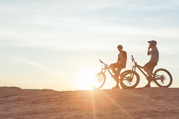 Fototapeta premium Bicycle, nature or friends on break at sunset for training, fitness or rest after workout with flare. Cycling, mountain bike and men relax in outdoor for exercise, sports or adventure with space