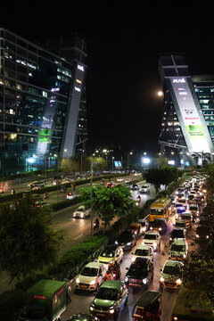 Night view of the Raghvendra Marg Road, business center buildings and vehicle traffic in Cyber City, Gurgaon, India.