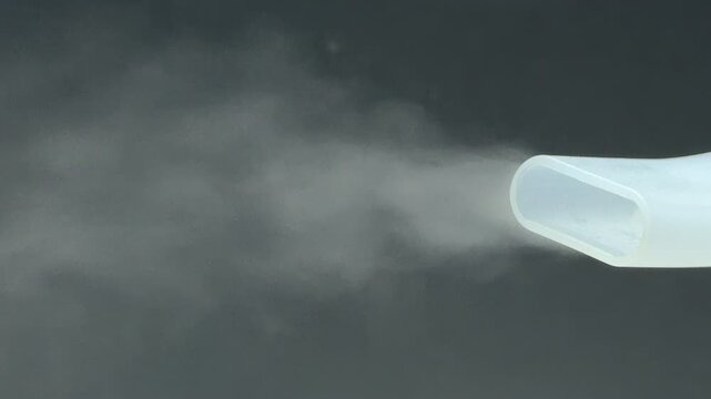 A medical nebulizer nozzle sprays a fine, soothing vapor against a dark background. The steady flow of mist creates a sense of relief and calm. This vital tool helps with easy breathing.