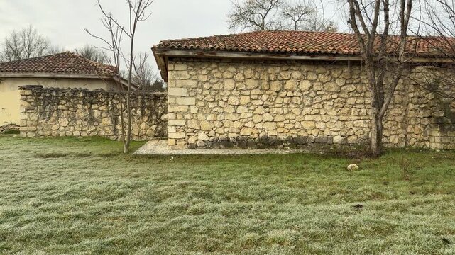Historic stone structures with red tiled roofs rest on a field of frost-covered grass. The scene feels lonely and quiet in the chilly morning air. It is a peaceful glimpse into the past.