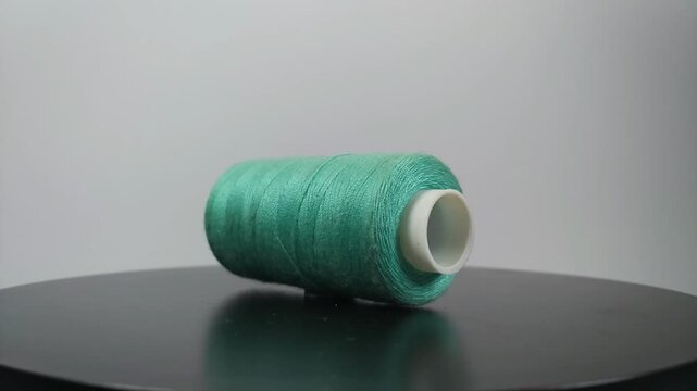 sewing thread lying sideways and rotating on clean surface.