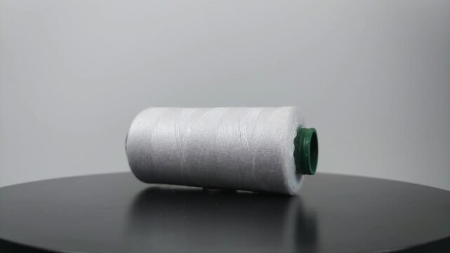 sewing thread lying sideways and rotating on clean surface.
