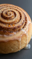 Fototapeta premium Close up cinnamon roll with glaze dripping on dark surface