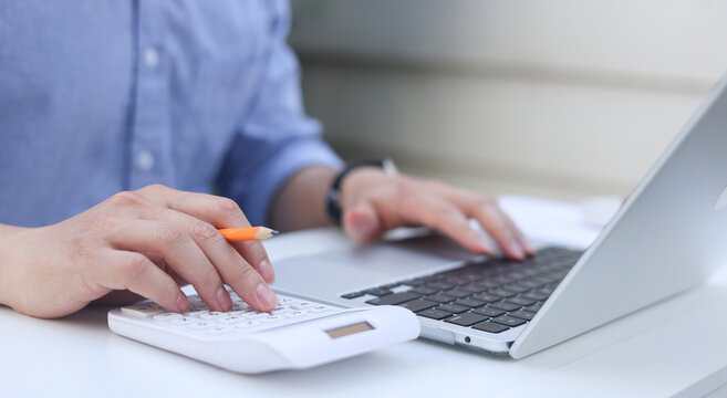 close up accountant woman press on calculator to check about profit or budget and debt of company at office desk for business financial concept