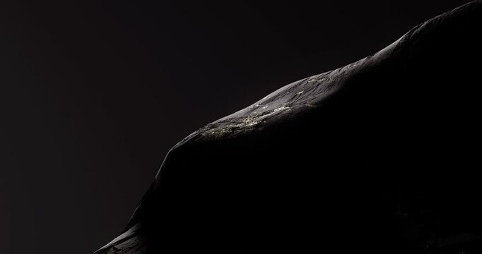 Close up of dark rock surface with golden mineral veins creating a rich textured abstract background.