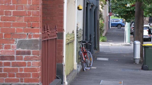 Quiet residential street in West Melbourne, Australia with heritage terrace houses, brick facades, and a bicycle parked along the footpath. Inner-city historic suburban homes and walkable urban living