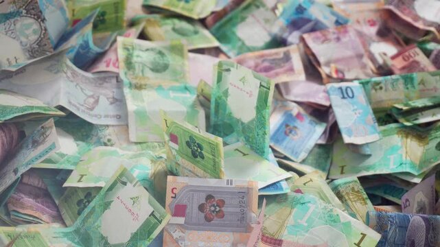 Close up vibrant pile of Qatari Riyal banknotes from the fifth series. Various colorful denominations 1, 10, and 50, showcasing Qatars modern currency and heritage. Charity box. Fundraiser. Lottery
