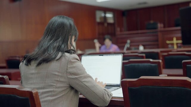 Rear view of courtroom with lawyer sitting, representing legal environment and justice system. Concept of court proceedings, law practice, and professional judicial atmosphere.