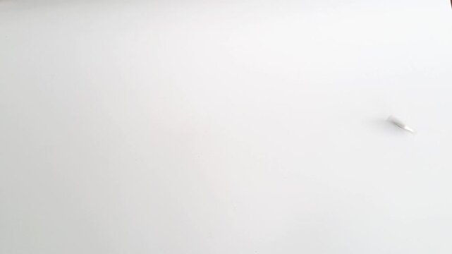 Horizontal shot of an Asian man's hands spinning a silver coin on a white minimalist background. This footage captures the concept of probability. PAMEKASAN, INDONESIA - APRIL 1, 2026