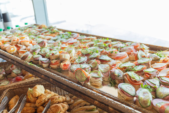 Catering with meats, fruits, cheeses and sandwiches. An assortment of cold cuts and canapes on wooden skewers