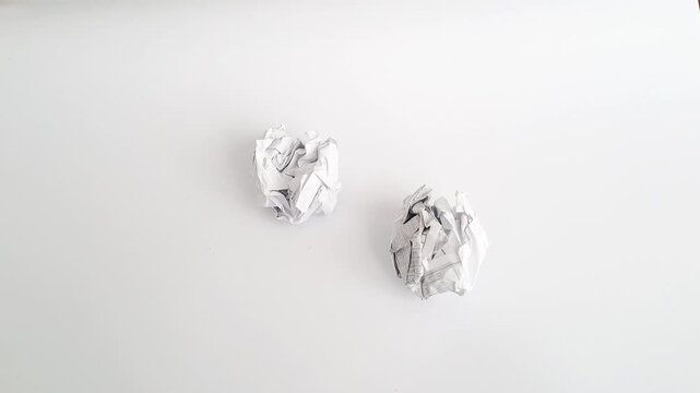 Close-up of an Asian man's hands crumpling a piece of white paper and throwing it away in anger. A minimalist horizontal shot depicting frustration, failure, creative block, and stress at work.