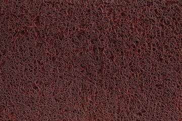 Fototapeta premium Red PVC coil mat texture. Durable vinyl spaghetti floor mat surface background in dark red color.
