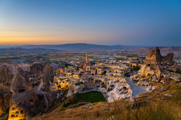 Fototapeta premium Fairy chimneys with the homes carved in a cliffs near Uchisar castle in twilight after sunset. Cappadocia, Turkey.