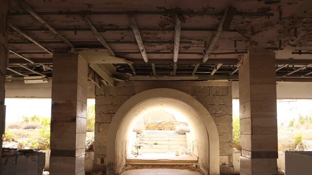 Somber interior shot of a ruined building in Ma'aloula, Syria, featuring traditional arches and war damage