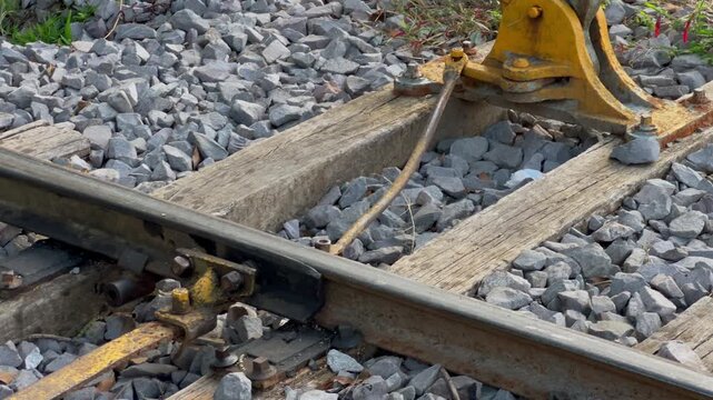 Railroad switch linkage is shown in detail as the camera moves laterally to reveal the manual lever mechanism beside the track.