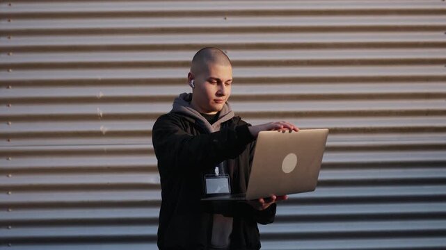 Young male it specialist finishing his remote work on a laptop and smiling confidently at the camera