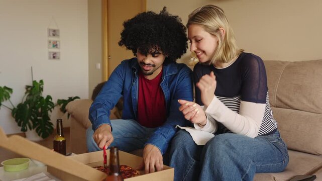 Young multicultural couple happily sharing pizza at home