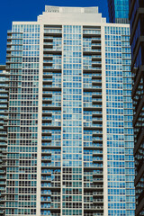 Fototapeta premium Modern building stands tall under clear blue sky in a busy city, showcasing glass and concrete design and capturing reflections from surrounding structures