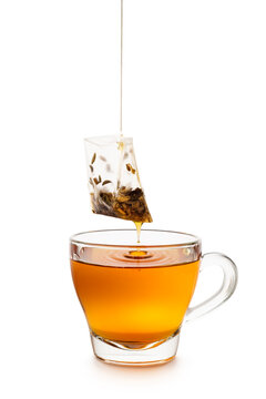 Glass cup of tea with dripping tea bag isolated on white background.