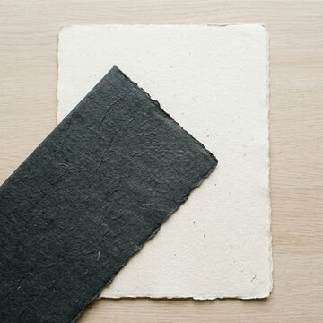 Overlapping handmade paper sheets in dark and light tones with rough edge