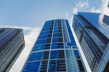 Fototapeta premium Tall buildings reach for the sky in a bustling city under a clear blue sky