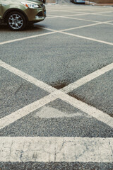 Fototapeta premium Parking lot with marked lines and a wet spot during the day in an urban area