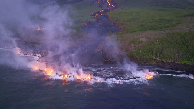Aerial view of lava flowing from Piton de la Fournaise into the ocean, creating a dramatic contrast of fire and water, Piton de la Fournaise, Saint-Benoit, Reunion.