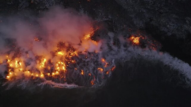 Aerial view of the fiery orange lava flowing from Piton de la Fournaise meeting the dark ocean waters, Sainte Rose, Saint-Benoit, Reunion.