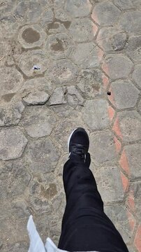POV Close-up of Man Feet Walking on Hexagonal Paving Blocks Wearing Black Sneakers
