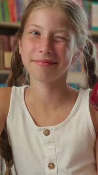 Happy Caucasian little girl child eating apple writing in copybook during school break indoor smiling pupil learn education snack time healthy habit kid schoolgirl student lunch fruit studying lesson