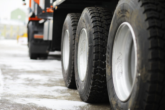 Close-Up of Heavy-Duty Truck Wheels on Snow-Covered Ground in Industrial Setting
