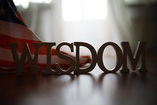 Wisdom Sign with American Flag in Background on Wooden Floor