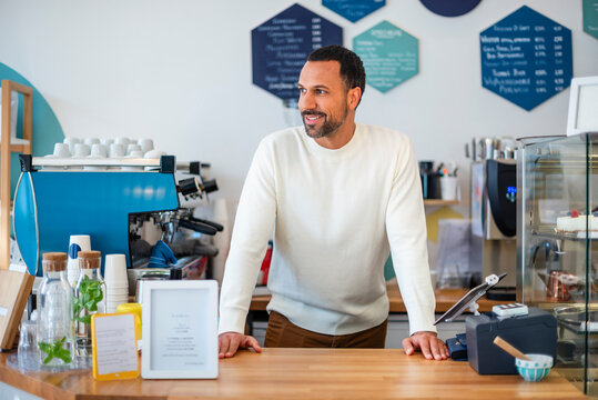 Barista standing behind counter in caf� looking satisfied