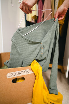 Hand placing clothing in donation box for sustainable fashion and reuse