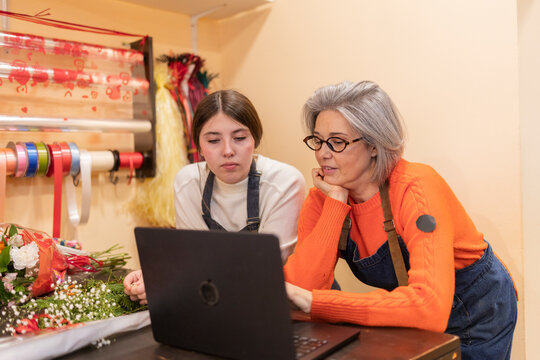 Florist explaining flower arrangement process with student in shop