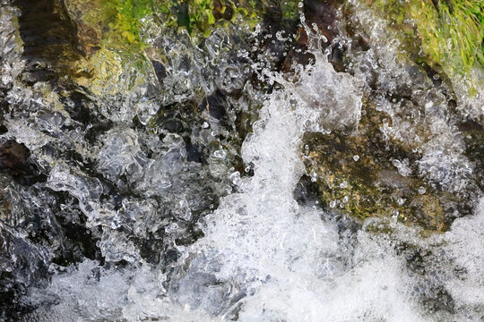 Flowing clear stream water splashing over rocks in Germany