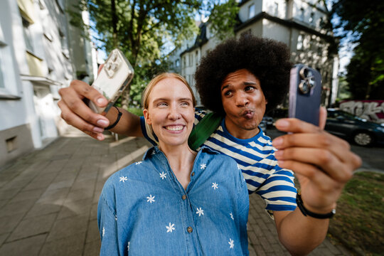 Friends taking a fun selfie while walking in an urban setting outdoors
