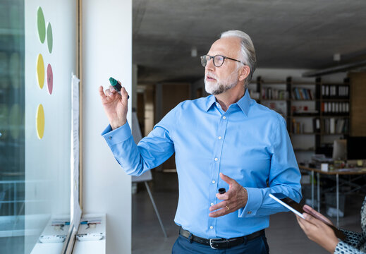 Businessman brainstorming with colleague during team meeting in modern office