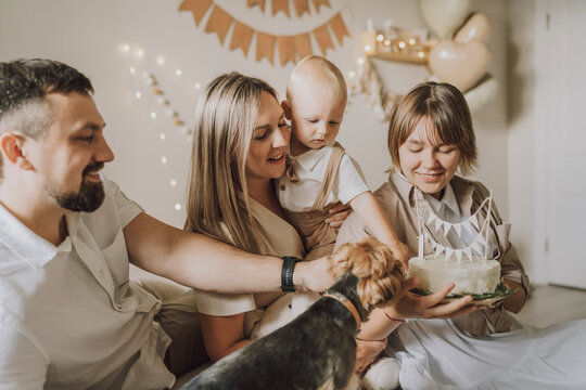 Family celebrating first birthday with cake and decorations at home