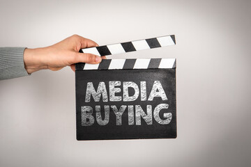 Obraz premium Media Buying Written on Clapperboard Held by Hand in Studio Setting