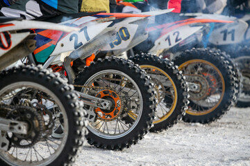 Row motocross dirt bikes lined up at starting line during winter racing competition