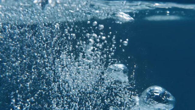Abundant tiny bubbles rising through dark blue liquid