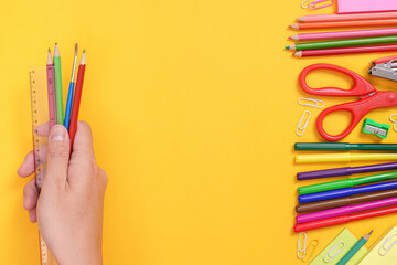 Fototapeta premium Hand holding pencils and ruler with school supplies