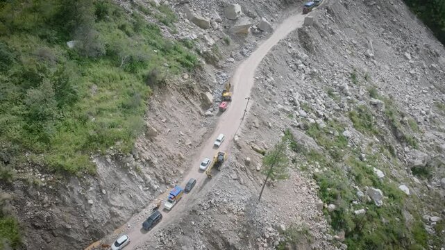 Drone view of vehicles slowly driving over a Dangerous road with Massive rock Landslide in Himachal Pradesh.