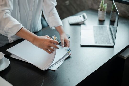 Business Professional Organizing Documents at Modern Office Desk with Laptop and Calculator
