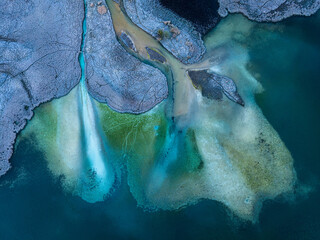 Above of abstract frozen lake shore with turquoise water and frost covered land © Mumemories