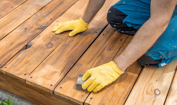 Worker applies wood stain with focused care